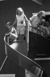 Two_children_preparing_to_use_a_curving_playground_slide,_1963